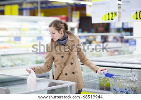 pretty young buying frozen fish/groceries in a supermarket/mall/grocery store (color toned image; shallow DOF)