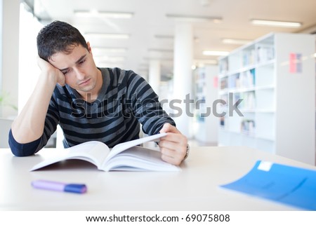 handsome young college student in a library, studying hard (shallow DOF; color toned image)