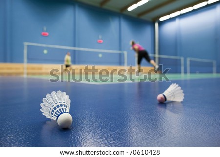 badminton - badminton courts with players competing; shuttlecocks in the foreground (shallow DOF; color toned image)