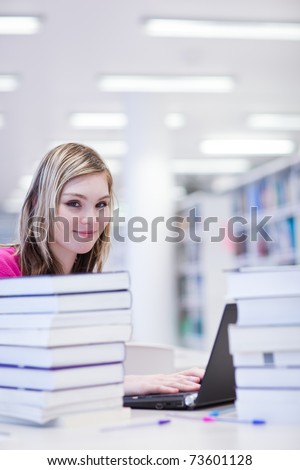 in the library - pretty, female student with laptop and books working in a high school/university library (color toned image)