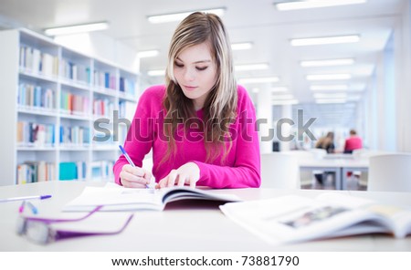 in the library - pretty, female student with laptop and books working in a high school library (color toned image)