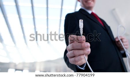 young businessman holding an ethernet cable - stressing the importance of fast and reliable internet connection for a business (color toned image; shallow DOF)