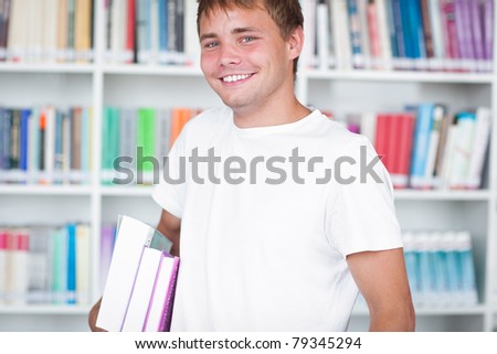 portrait of a handsome college student standing in a college/university library, smiling (color toned image)