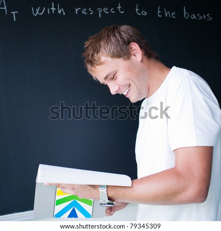 handsome college student solving a math problem during math class in front of the blackboard/chalkboard (color toned image)