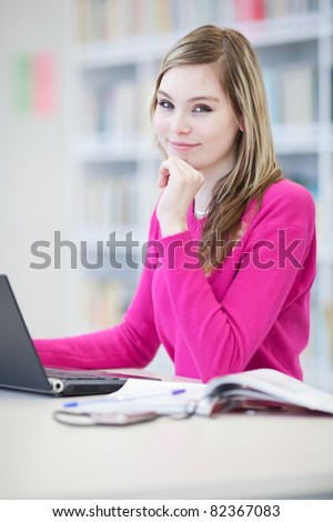 in the library - pretty, female student with laptop and books working in a high school library (color toned image)