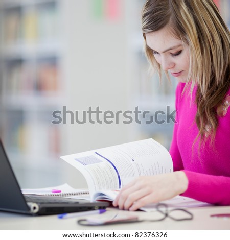 in the library - pretty female student with laptop and books working in a high school library (color toned image)