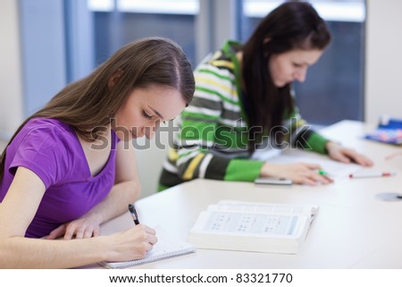 in the library - two female students with books working in a high school library (color toned image)