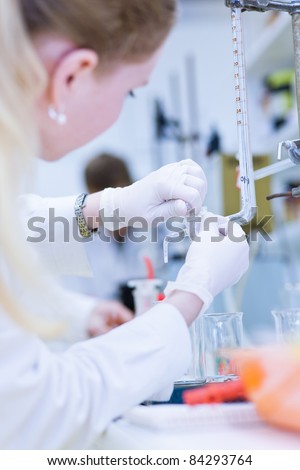 female researcher carrying out research in a chemistry lab (color toned image; shallow DOF)