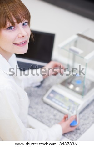 pretty female researcher using a microscope in a lab