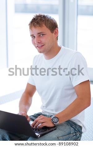 handsome college student using a computer in a college/university library/study room (color toned image)