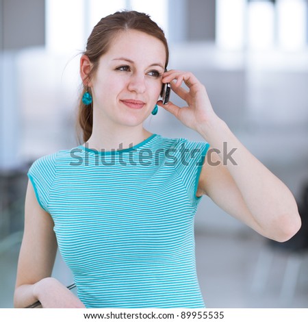 Pretty, young woman using her mobile phone/speaking on the phone in a public area (shallow DOF; color toned image)