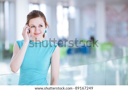 Pretty, young woman/college student using her mobile phone/speaking on the phone in a public area (shallow DOF; color toned image)