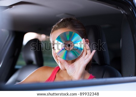 Young female driver playing music in the car (changing CDs)