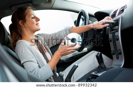 stock photo Young female driver playing music in the car changing CDs 