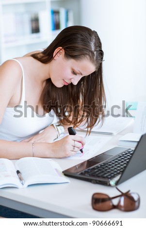 pretty female college student studying in the university library/study room (color toned image)