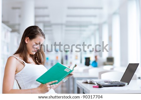 pretty female college student studying in the university library/study room (color toned image)