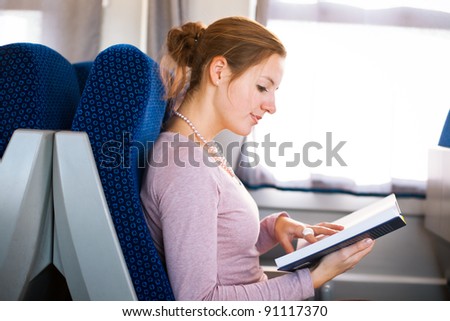 Young woman reading a book while on a train