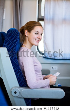 Young woman traveling by train, holding her train ticket , smiling