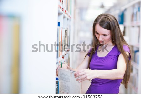 in the library - pretty female student with laptop and books working in a high school library (color toned image)