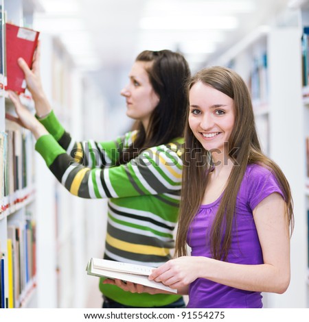 in the library - pretty female student searching for a book in college/university library