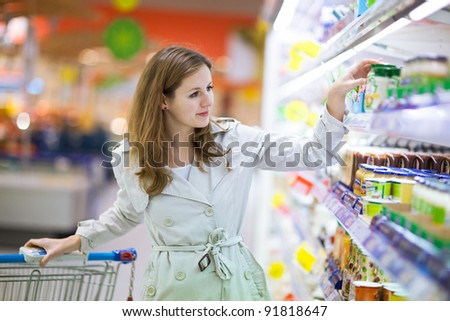 Beautiful young woman shopping for fruits and vegetables in produce department of a grocery store/supermarket (color toned image)