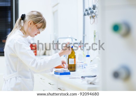 female researcher carrying out research experiments in a chemistry lab (color toned image)