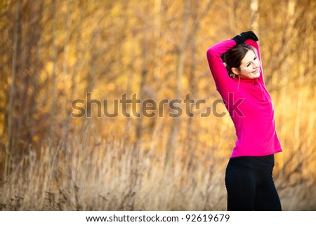 Young woman stretching before her run outdoors on a cold fall/winter day