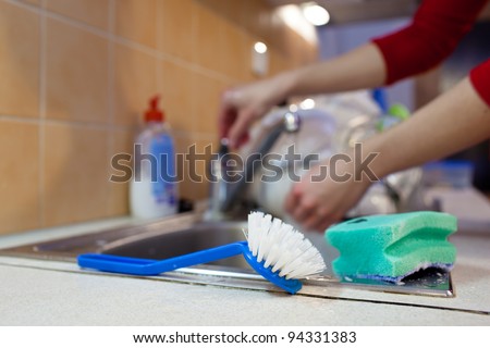Washing of the dishes - woman hands rinsing dishes under running water in the sink
