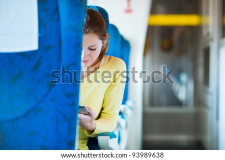 Young woman using her tablet computer while traveling by train (color toned image; shallow DOF)