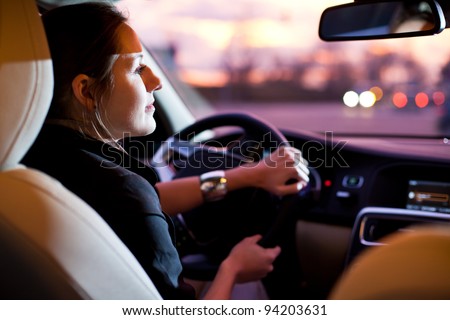 Driving a car at night - pretty, young woman driving her modern car at night in a city (shallow DOF; color toned image)
