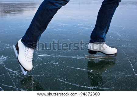 Young woman ice skating outdoors on a pond on a freezing winter day
