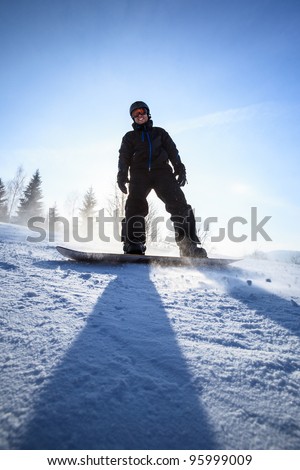 Young man snowboarding down a slope on a lovely sunny winter day