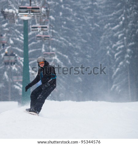 Young man freeride snowboarding off-piste in snow in a mountain resort  on a snowy winter day
