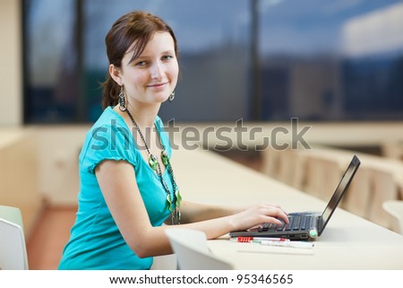 Pretty young female student with laptop on college/university campus