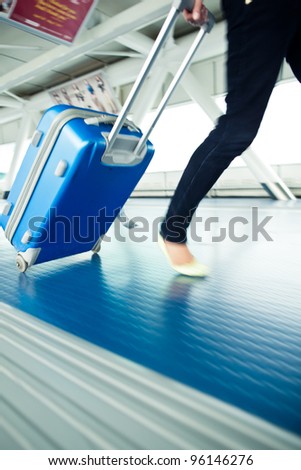 Airport rush: people with their suitcases walking along a corridor (motion blurred image; color toned image)
