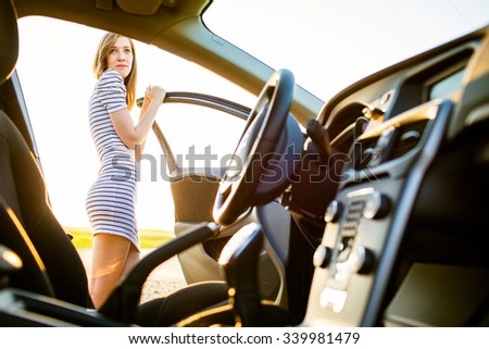 Portrait of a pretty, female teen driver, by her new car