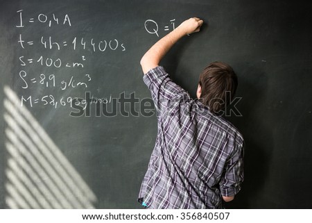 College student solving a math problem during math class in front of the blackboard/chalkboard (color toned image)