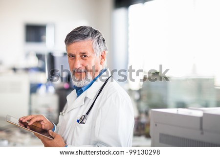 Senior doctor using his tablet computer at work color toned image Senior doctor using his tablet computer at work color toned image