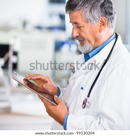 Senior doctor using his tablet computer at work color toned image Senior doctor using his tablet computer at work color toned image