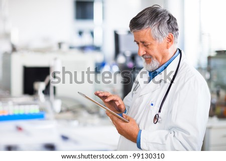 Senior doctor using his tablet computer at work (color toned image)