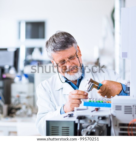senior male researcher carrying out scientific research in a lab using a gas chromatograph (shallow DOF; color toned image)