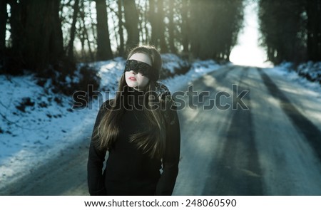 Girl with a blindfold on the background of gloomy road
