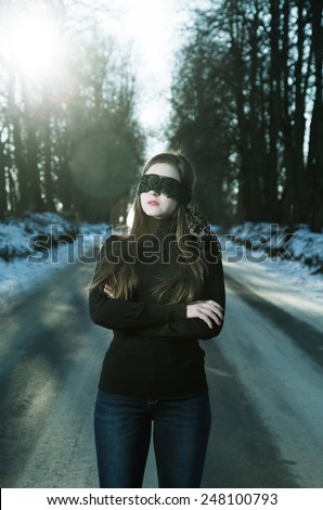 Girl with a blindfold on the background of gloomy road