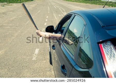 Driver with a baseball bat on the road