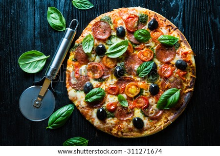 Pizza with salami, olives and basil