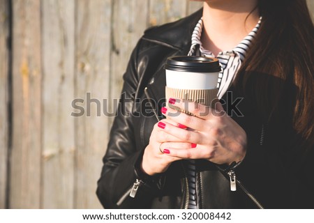 Paper cup with coffee in hand at the girl