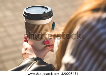 Paper cup with coffee in hand at the girl