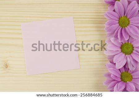 Blank pink card and pink flowers on wooden background