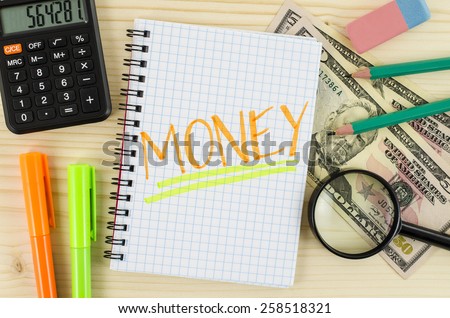 Notebook with money word and office tools on wooden table