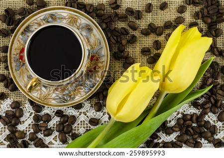 Porcelain coffee cup with yellow flowers and coffee beans on linen background